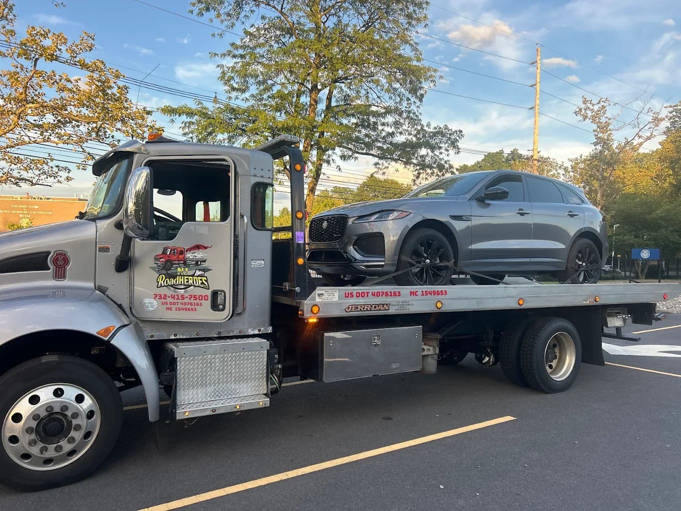 Road Heroes flatbed tow truck transporting a Jaguar F-Pace SUV
